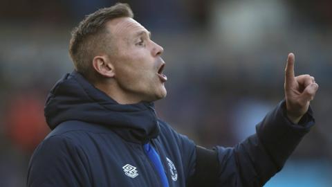 Shrewsbury Town manager Matt Taylor looks on from the dugout during a match