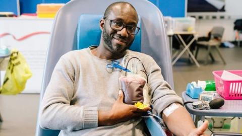 Black man giving a thumbs up while he donates blood