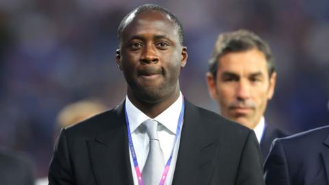 Yaya Toure on the touchline wearing a suit