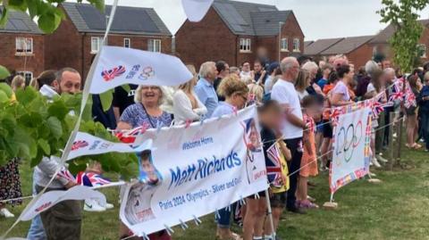 A large group of people holding banners with Matt Richards' name on the front