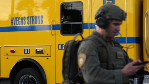 A law enforcement officer walks by an ambulance with the words 'Vegas Strong'