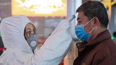 Medical staff check the temperature of passengers at Nanjing South Railway station in Nanjing, Jiangsu Province, China, 27 January 2020