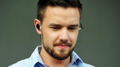 Liam Payne looking down with an earpiece in on stage in 2018