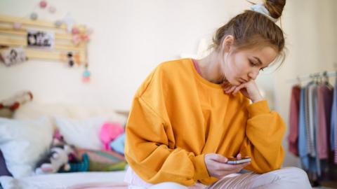 Young woman sitting alone in her room