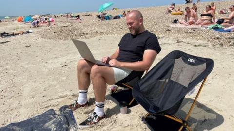 Man checking his email on the beach at Southsea