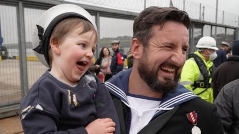 Sailor holding boy celebrating reunion with family