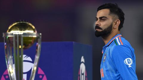 India's Virat Kohli looks on and walks past the Cricket World Cup trophy after their defeat by Australia in the final