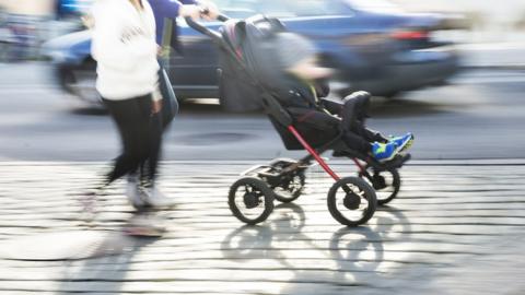 Pushing a pram along a busy road