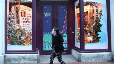 A woman walks past a closed shop in Belfast