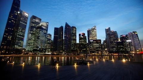 People walk past the skyline of Marina Bay central business district in Singapore 26 April 2013