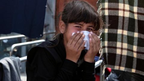 A girl reacts to tear gas fired by riot police