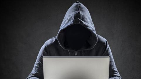 Computer hacker stealing data from a laptop - stock photo