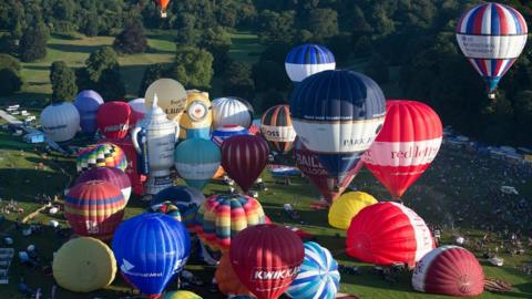 Hot air balloons inflated and ready to take off, seen from the sky over Ashton Court