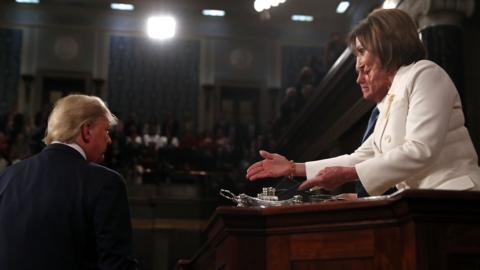 Speaker of the US House of Representatives Nancy Pelosi (R) extends her hand to US President Donald Trump