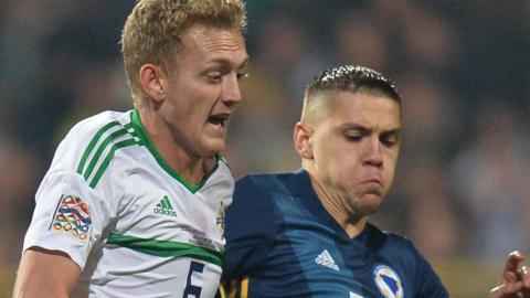 NI midfielder George Saville tussles with Bosnia-Herzegovina's Muhamed Besic