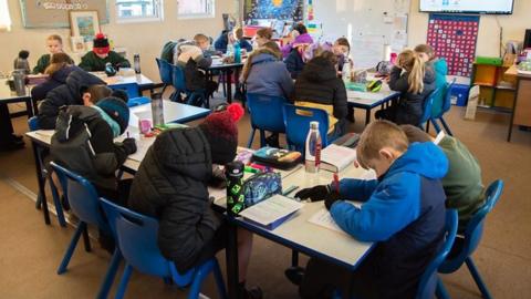 Pupils with coats on in a classroom