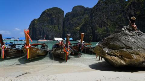 Boats and a tourist on Maya Bay before it was closed