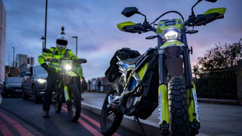 Two e-bikes clad in yellow and Police writing. One officer in a white helmet is on a saddle