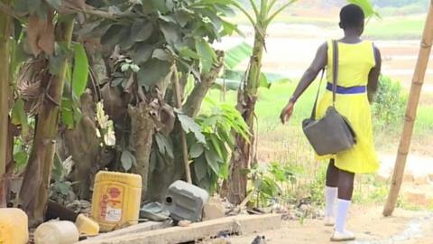 Ghanaian schoolgirl walking across river