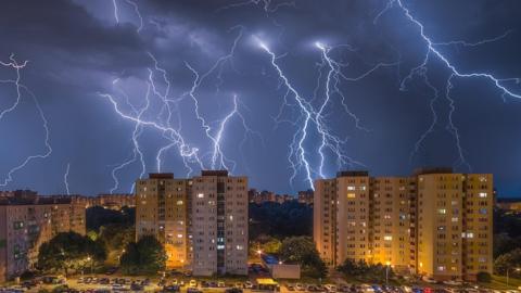 Lightning striking behind tall buildings