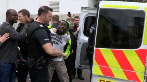 Adam Jameh being taken away from police