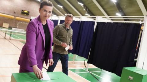 Danish Prime Minister Mette Frederiksen, also leader of Denmark's Social Democrats, casts her ballot as her husband Bo Tengberg looks on at a polling station in Vaerloese near Copenhagen, Denmark, on June 1, 2022