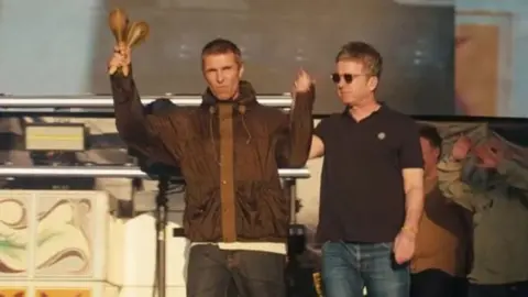 Liam and Noel Gallagher hand-in-hand arrive on stage