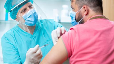 Medic administers jab to man in pink shirt