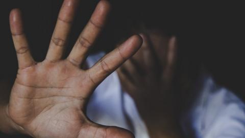 A Nigerian with head bowed holds out her hand in protest