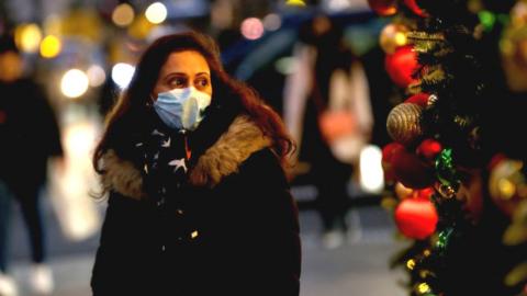 A woman in a mask next to a Christmas decoration