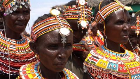 women in bright red and yellow beaded headdresses.