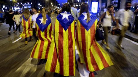 People wearing "Estelada" Catalan flags on their backs leave after taking part in a protest in Barcelona (3 October 2017)