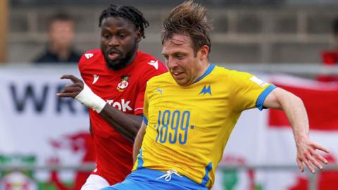 Tom Lapslie of Torquay United battles for the ball with Jacob Mendy of Wrexham