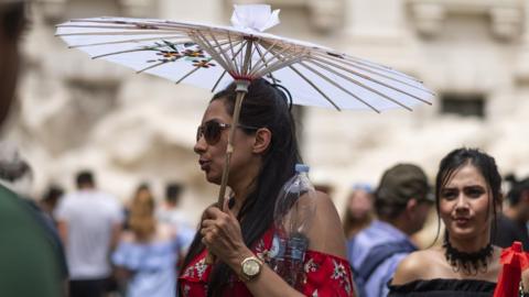 A tourist holds a sun umbrella in Rome, Italy.