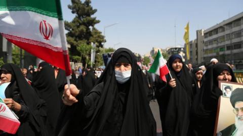 People march with flags and banners to celebrate Iran's April 13 attack on Israel and protest Israel
