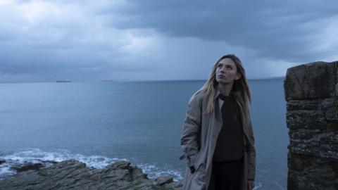 Sian Eleri standing on a cliff top looking up at the sky