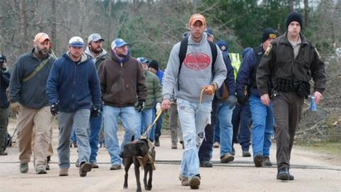 A search and rescue team walk past damage from a tornado which killed at least 23 people in Beauregard, Alabama.