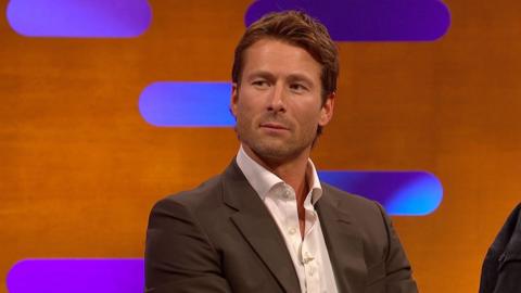 Glen Powell on the Graham Norton show wearing a brown suit and a white shirt
