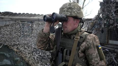 A Ukrainian serviceman patrols at the checkpoint in the village of Shyrokyne near Mariupol, in eastern Ukraine, April 2021