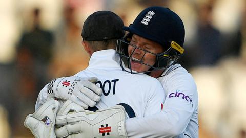 Joe Root and Ollie Pope embrace after England take a late wicket