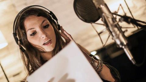 Staged photo of a young woman at a microphone