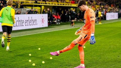 Tennis balls are cleared away from the pitch during Borussia Dortmund's game against Freiburg