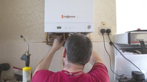 A plumber installs a new boiler