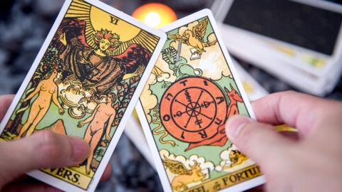 Stock image of a person holding two tarot cards