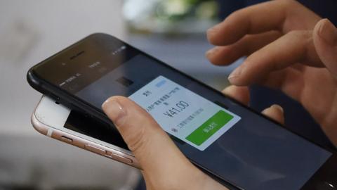 A woman making purchases through her smartphone at a shop in Beijing on 23 July 2017