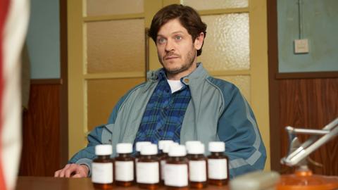 Iwan Rheon in the new 鶹Լ series Men Up, pictured sitting at a table in front of pill bottles