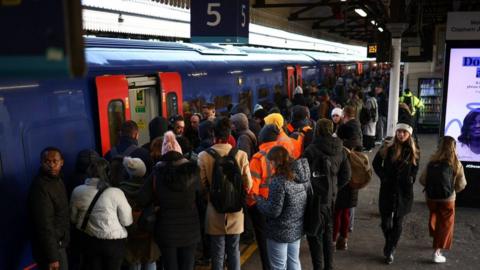 File image of passengers queuing to get on a South Western Railway train at Clapham Junction station.