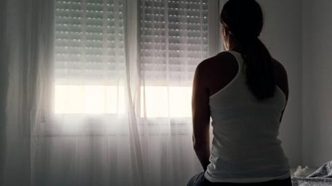 woman sits alone opposite window