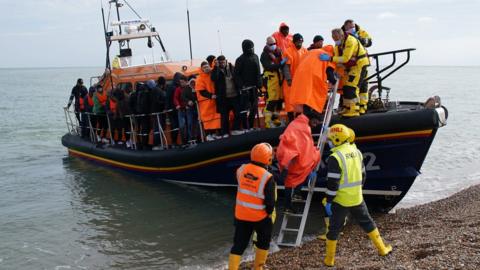 A group of people thought to be migrants are brought in to Dungeness beach by lifeboat on 12 October