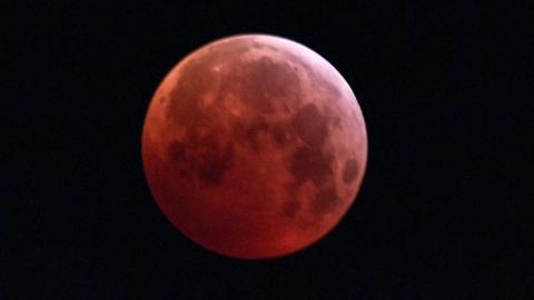 The so-called Super Blood Wolf Moon is engulfed into Earth's dark umbral shadow during a total lunar eclipse over Milan, north Italy on January 21, 2019